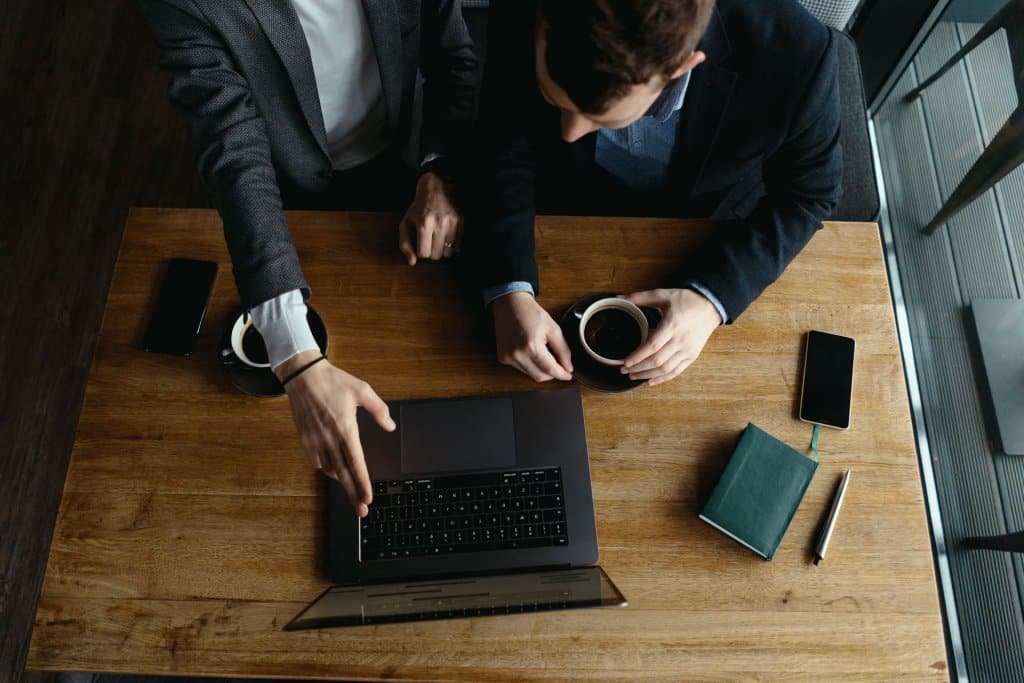 two businessmen pointing to laptop screen